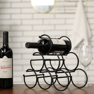Iron tabletop wine rack, black metal; two wine bottles and a glass visible nearby.