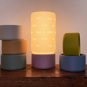 Liunk Table Lamp by Terra Labs; ribbed warm shade on purple base, with a lime-green lamp on a blue base nearby, 2 lamps