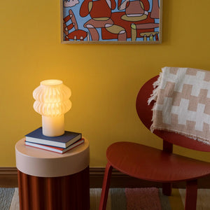 Oppi Table Lamp by Terra Labs with a white ribbed glass shade on a white base beside books.