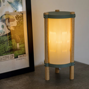 Toro Table Lamp featuring a wooden ribbed shade with teal metal bands and a warm glow.