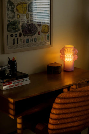 Oppi table lamp by Terra Labs on a wooden desk; pink ribbed glass, warm glow
