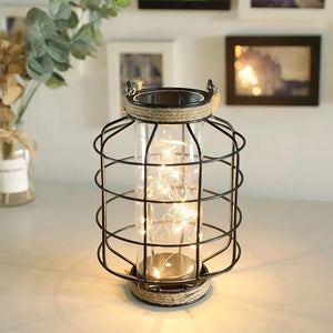 9.4 in tall battery-powered table lamp by JHY DESIGN; black metal cage, glass jar, warm string lights.