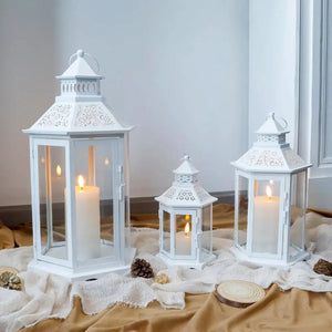 Set of 3 white hexagonal decorative hanging lanterns with lit candles, 18, 13 and 10 inches tall.