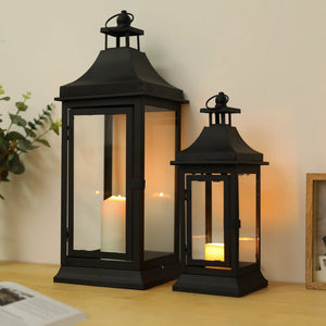 Outdoor candle lanterns set of 2: black metal lanterns, 13in and 19.5in tall, with glass panels and lit candles.