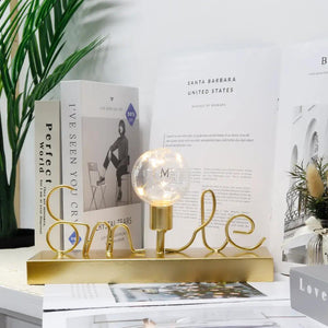 Decorative cordless lamp with a globe bulb and warm white fairy lights on a gold base.