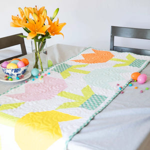Spring Tulip Table Runner quilt kit by Block Party Quilt Co on a table with Easter eggs and orange lilies.