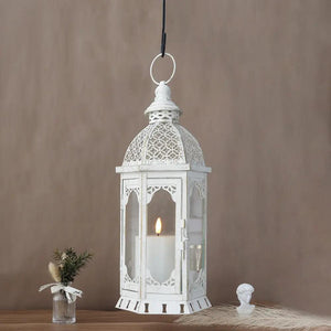 15-inch-tall outdoor candle lantern in vintage white metal with ornate lattice detailing and a lit candle visible inside
