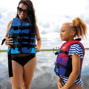 WOW Watersports Vis-Wave adult life vest blue with black straps; two people wear blue and red life vests.