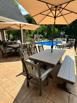 Trestle X Outdoor Bench gray weathered wood dining set under beige umbrellas beside the pool by Wooden Whale Workshop.