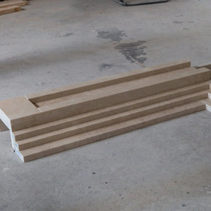 Beige marble fireplace mantel pieces stacked on a concrete workshop floor.