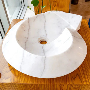 Carrara marble helix shape above-counter bathroom sink by Villohome, polished white with gray veining.