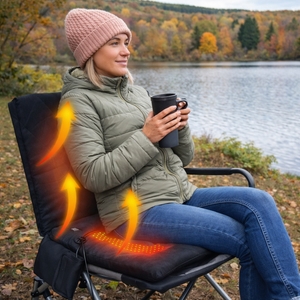Heated outdoor seat cushion with backrest in black on a camping chair beside a lake in autumn
