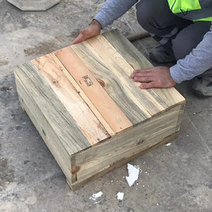Wooden shipping crate on a concrete floor, worker in a high-visibility vest inspecting it