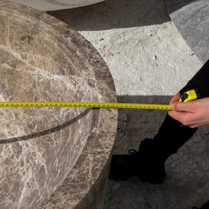 Emperador Light marble bathtub by Villohome; brown veined solid marble edge with tape measure across