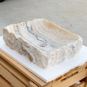 Honey onyx rectangular above-counter bathroom sink with polished interior and hand-chiseled exterior.