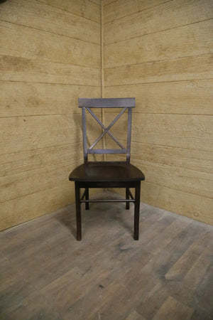 Single X Chair by Wooden Whale Workshop; dark wood chair with an X-back in a corner.