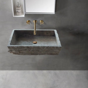 Wall-mount bathroom sink in silver travertine with brass faucet.