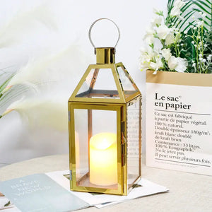 16 inch high decorative lantern with a rose gold metal frame, glass panels and a lit candle inside
