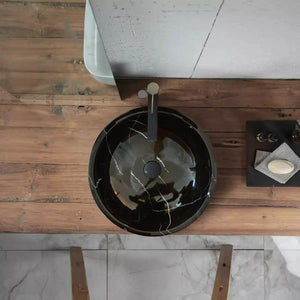 Natural Stone Toros black marble round vanity sink on a rustic wood countertop with a tall metal faucet