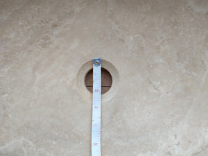 Troia Light travertine bathroom vanity sink cutout on stone countertop with measuring tape