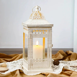 Decorative candle lantern, beige distressed metal with gold brush accents, 14.5in tall with glass panels and lit candle