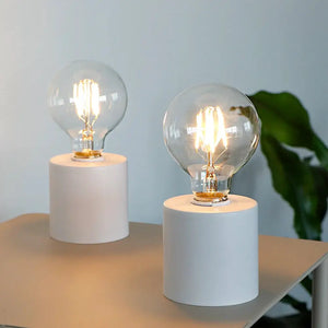 Set of 2 white 7-inch tall battery-operated table lamps with cylindrical bases and clear glass bulbs by JHY DESIGN