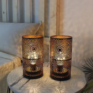 Set of 2 black metal patterned table lamps with cutout lattice, battery-operated on a round marble table