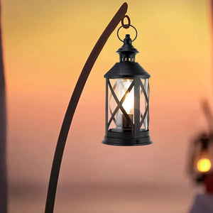 Battery-powered black metal lantern with glass panels and hanging hook, 10-inch height for outdoor decor.
