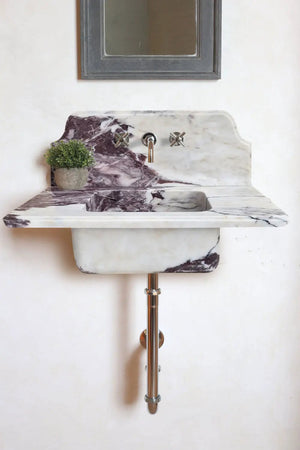 Calacatta Viola marble bathroom sink, wall-mounted with 10-inch backsplash; includes small plant.