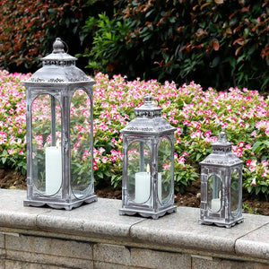 Set of 3 cement-gray decorative candle lanterns with vintage design, displayed outdoors among pink flowers.