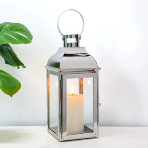 12.5-inch high decorative lantern by JHY DESIGN with a silver metal frame, glass panels, and a lit candle inside.