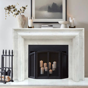 Villohome Carrara white marble fireplace mantel with polished veining, black firebox, and several candles.