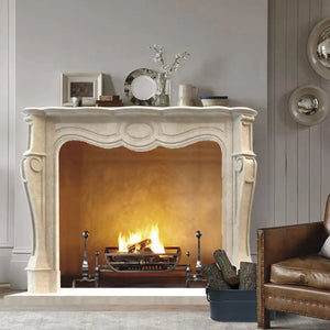 Crema Marfil marble French Villa Style hand-carved fireplace surround, cream-white with a lit fire.