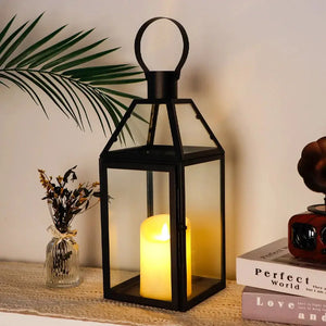 16-inch high black metal decorative lantern with glass panels and a loop handle, housing a warm candle.