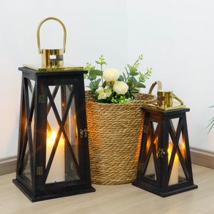 Set of 2 farmhouse decorative candle lanterns, 12in and 18in, with black trapezoid bases and gold metal frames