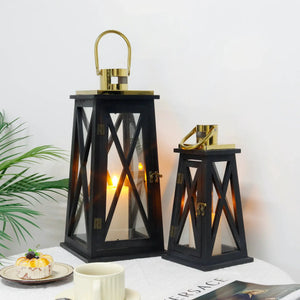 Set of two black trapezoid farmhouse lanterns with glass panels and gold hardware; decorative candle lanterns, 12" and 18" tall.