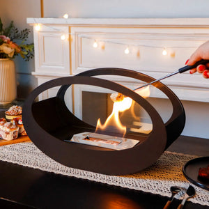 Black metal circular tabletop fireplace with glowing flame on a cozy home setup