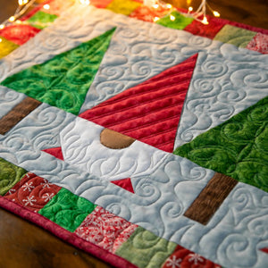 Christmas Gnomes Quilted Table Runner with red, green and light blue patchwork and swirled quilting; precut quilt kit