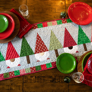 Quilt kit table runner with Christmas patchwork in red, green, and white on a wooden table