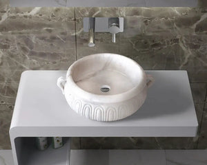 Calacatta white marble vessel sink with a carved exterior on a gray bathroom vanity with a wall-mounted faucet