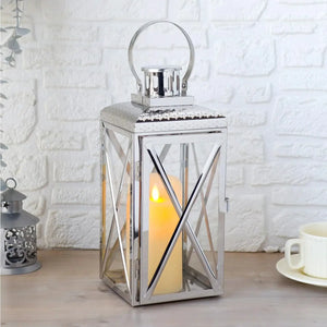 14-inch square stainless steel lantern with glass panels and a top circular handle, candle lit inside.
