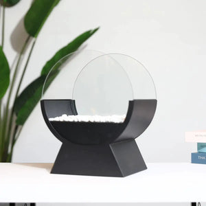 13.5-inch tall tabletop fireplace in black with a round glass guard, white decorative pebbles, and a small flame
