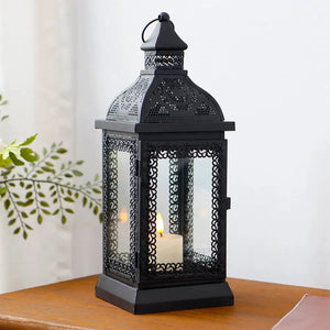 Rustic black metal candle lantern, 13in tall, with ornate perforated panels and a lit candle inside