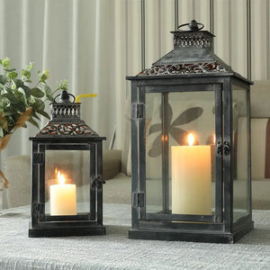 Set of 2 antique grey brush decorative candle lanterns with glass panels, ornate vented tops, and lit candles.