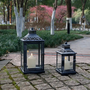 Antique grey brush decorative lanterns, metal frames with glass panes and lit candles inside, set of 2