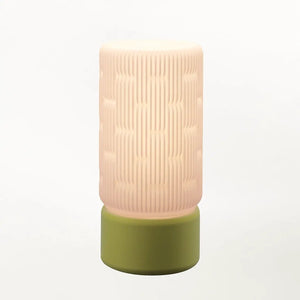 Liunk table lamp with a pale pink ribbed shade atop an olive-green base.