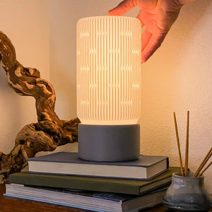 Liunk table lamp by Terra Labs with a white ribbed shade and dark base.