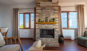 Ferrara Old School brick veneer fireplace in a living room with wooden floors and large windows.