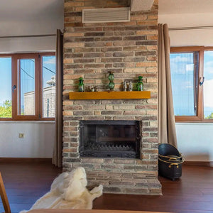 Ferrara Old School brick veneer fireplace surround with warm brick tones and wooden mantel in living room