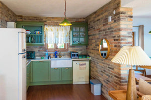 Ferrara Old School brick veneer in a kitchen with green cabinetry; handmade stone look.